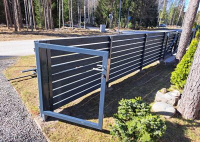 Metallaed ja tiibvärav paigaldus Harjumaal – horisontaalne must aed männimetsa serval