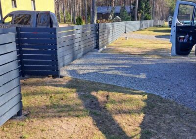 Horisontaalse laudisega aed metallpostidel eramu krundil männimetsa servas, Harjumaa